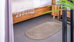 Quarto com cama de madeira, tapete tecido e ventoinha no teto.
