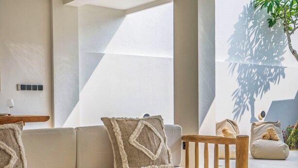 Uma área de estar moderna com sofá, mesas de madeira e ventilador de teto.