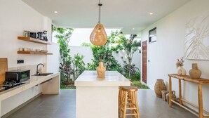 Uma cozinha moderna com ilha central, banquetas de madeira e luminária pendente.