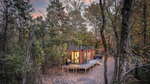 Une cabane dotée d’une terrasse, entourée d’arbres.