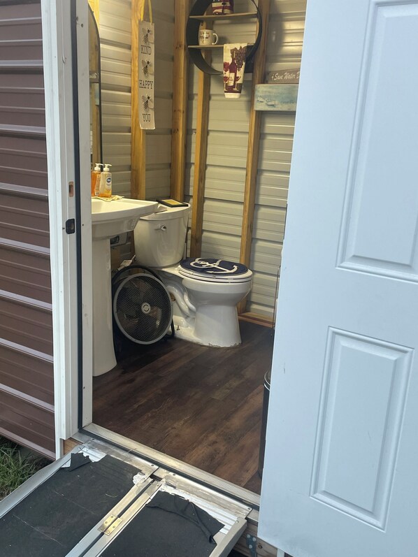 A small, compact bathroom with a toilet, sink, and fan.