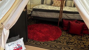A tented room with a bed, a red rug, and a decorative pillow. - Redfish at Eufaula, AL (Eufaula)