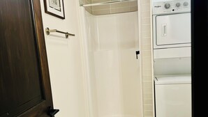 Une salle de bain équipée d’une douche, de toilettes et d’un lave-linge Whirlpool.
