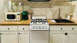 Une cuisine équipée d’un four à micro-ondes, d’une machine à café, d’une cuisinière à gaz et d’un évier.
