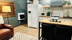 Une cuisine compacte équipée d’un réfrigérateur, d’un four à micro-ondes, d’une cuisinière et d’un petit coin repas avec une table et des chaises.