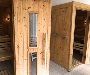 Una sauna in legno con porta in vetro, una maniglia in metallo e un porta asciugamani.