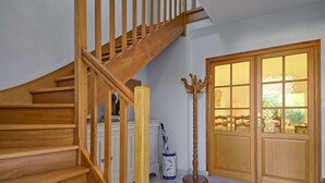 A wooden staircase leading to a landing, a door with glass panels, and a coat stand. - Villa au Parc Ny by Interhome (Pénestin)
