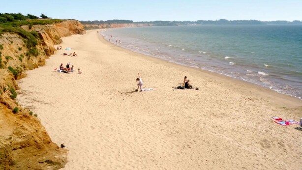 A sandy beach with people sunbathing and walking along the shore. - Villa au Parc Ny by Interhome (Pénestin)