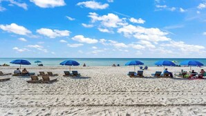 A beach with rows of sun loungers and umbrellas, a clear sky, and the ocean in the background. - The Summit 301 (Panama City Beach)