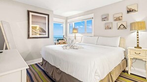 A hotel room with a large bed, a desk, a lamp, and a window with a view. - The Summit 301 (Panama City Beach)