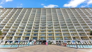 A high-rise hotel with multiple balconies, a swimming pool, and a clear sky. - The Summit 301 (Panama City Beach)