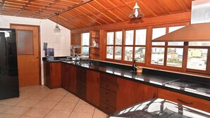 A kitchen with wooden cabinets, a black countertop, a stove, and a window with a city view.