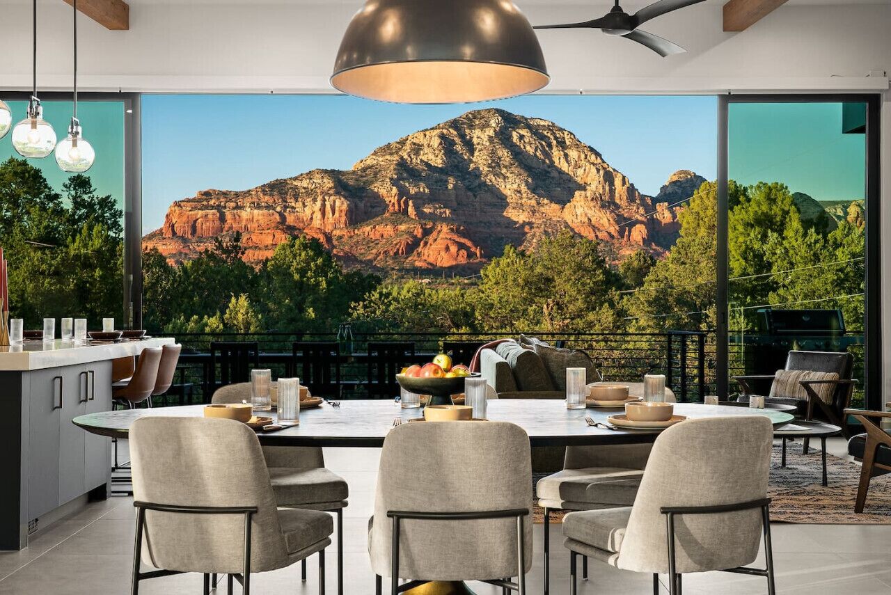 Un'area pranzo moderna con un tavolo grande, sedie e vista su una montagna.