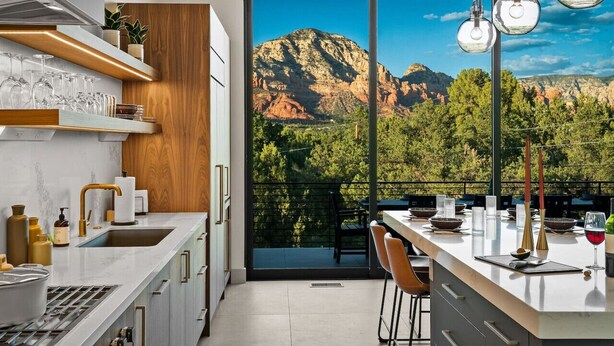 Eine moderne Küche mit großem Fenster und Blick auf eine gebirgige Landschaft.
