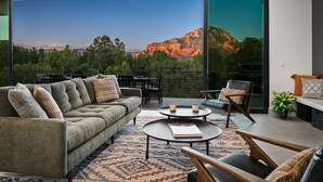Ein modernes Wohnzimmer mit einem großen Schiebeglastür, die auf einen Balkon mit Bergblick führt.