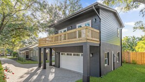 Ein zweistöckiges Haus mit überdachter Veranda, Garage und gepflegtem Rasen.