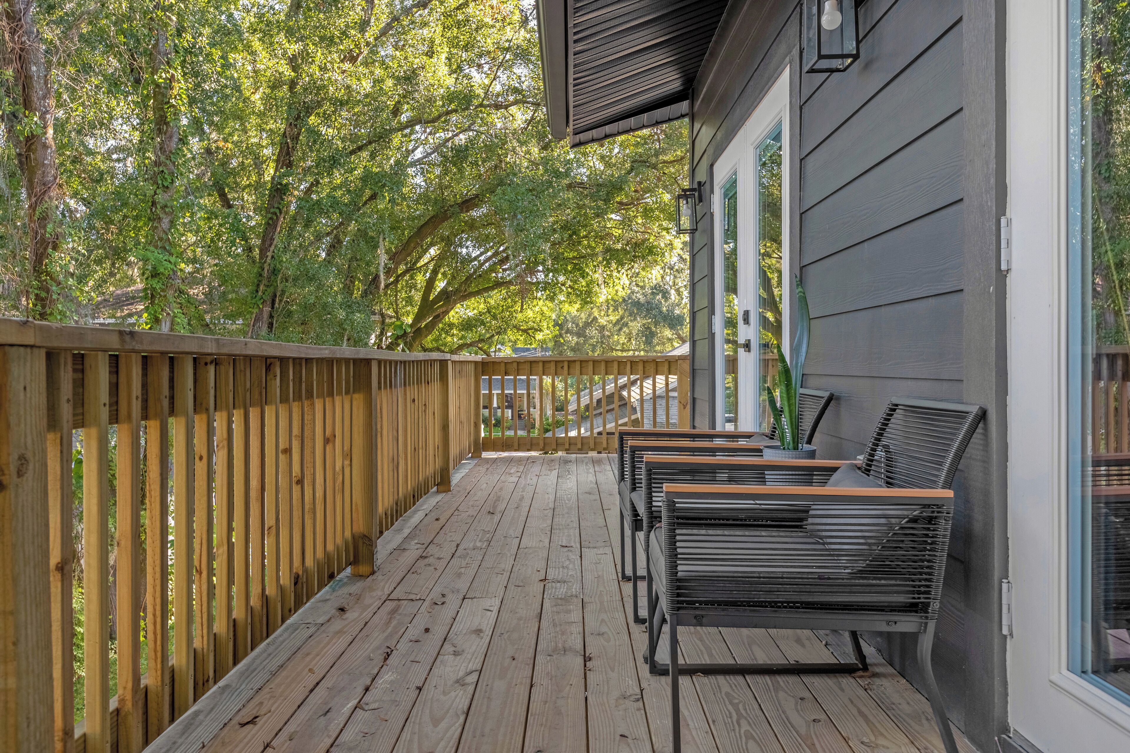 Une terrasse en bois avec des sièges d’extérieur et une vue sur les arbres.
