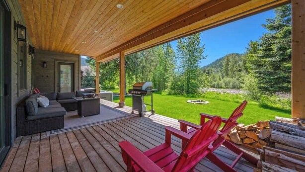 A covered deck with a wooden ceiling, outdoor seating, and a grill. - Idaho Club Golf Course | Luxe Living & Hot Tub (Sandpoint)