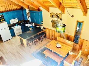 A kitchen with blue cabinets, a stove, and a sink. There is a dining area with a wooden table and benches.