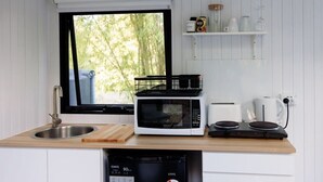 A compact kitchen with a sink, a microwave, a toaster, a coffee maker, and a dish rack.