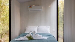 A room with a bed, white pillows, a teal bedspread, and a swan-shaped towel decoration.