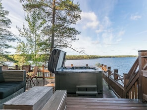 A hot tub on a wooden deck with a view of a lake and forest. - Nuottarinne by Interhome (Keuruu)