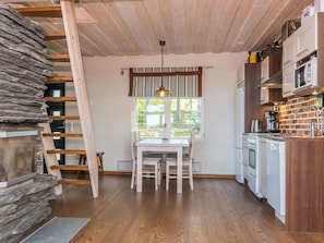 Eine Küche mit Holztisch, Stühlen, Herd und Kühlschrank.