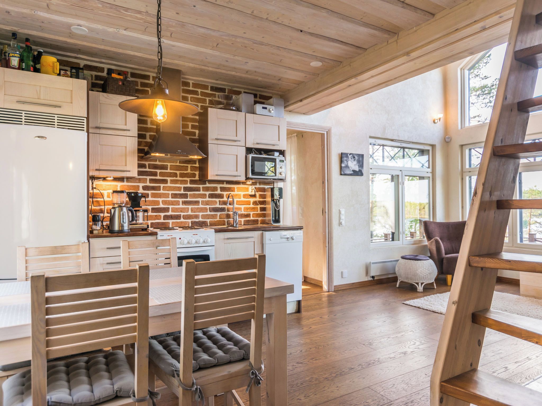 Une cuisine moderne avec un mur en briques, des armoires en bois et un coin repas comprenant une table et des chaises en bois.