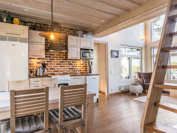 Una cocina moderna con pared de ladrillo, armarios de madera y un área de comedor con mesa y sillas de madera.