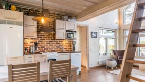 Una cocina con armarios de madera, una pared de ladrillo y un comedor con sillas de madera.