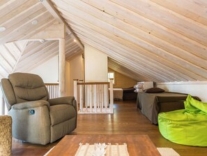 A loft-style room with a sloped ceiling, a cushioned chair, a bean bag, and a bed with pillows. - Nuottarinne by Interhome (Keuruu)
