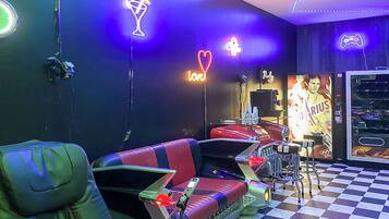 A room with a checkered floor, a neon-lit wall, a sofa, a gaming console, and a poster of a sports figure.