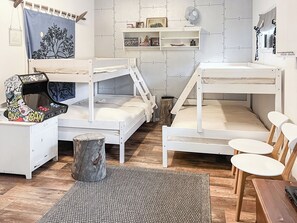 A bunk bed room with a desk, shelves, and a fan.