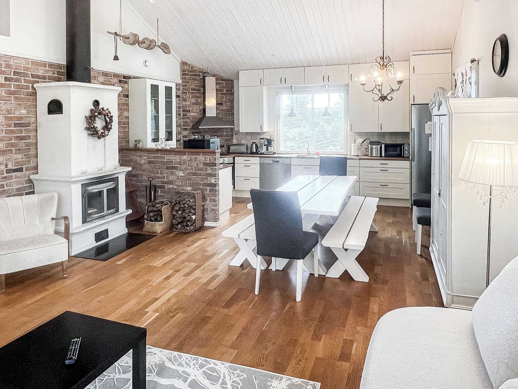 A modern kitchen with white cabinets, a dining area with a white table and chairs, and a fireplace.