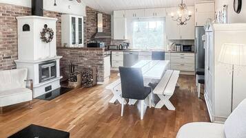 A modern kitchen with white cabinets, a dining area with a white table and chairs, and a fireplace.