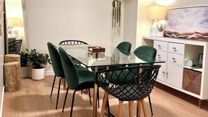 A modern dining area with a glass table and chairs, wooden flooring, a white cabinet with drawers, and a hanging plant. - Spacious & bright 2 bedroom suite with full kitchen and in-suite laundry!  (Langley Township)