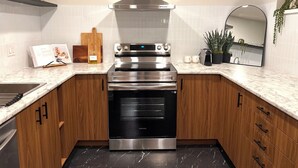 A modern kitchen with a stainless steel oven, wooden cabinets, a marble countertop, and a built-in stove. - Spacious & bright 2 bedroom suite with full kitchen and in-suite laundry!  (Langley Township)