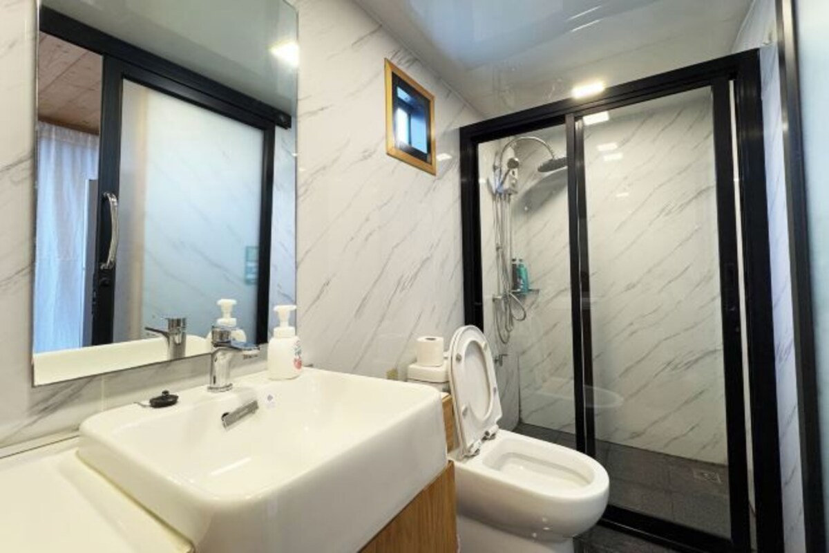 Un baño moderno con un lavamanos blanco, un inodoro y una ducha con mampara de vidrio.