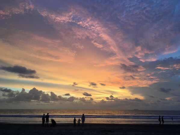 A beach scene with people walking along the shore, under a colorful sunset sky. - Abrite House - Tiny House Koh Lanta (Ko Lanta)
