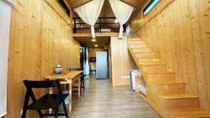 Interior de una cabaña de madera con comedor, una escalera y una cocina.