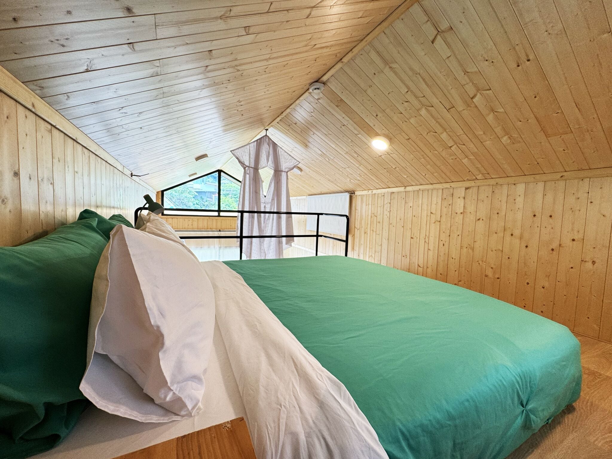 Una habitación con dos camas, paredes de madera, una ventana y vista a zonas verdes.