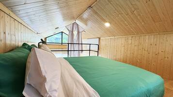 Una habitación con dos camas, paredes de madera, una ventana y vista a zonas verdes.