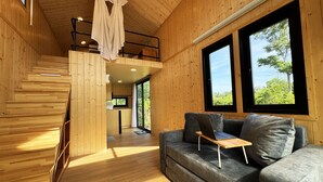 Un interior de madera con un sofá, una laptop sobre una mesa y una escalera.