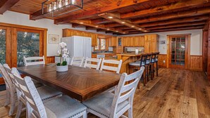 A spacious kitchen with wooden cabinets, a large island, and a dining area with a wooden table and chairs. - Perfect for couples, families, or small groups, this retreat blends serenity with style for an unforgettable getaway. Plenty of amenities to keep the family entertained indoors and out! (Mount Pleasant Mills)