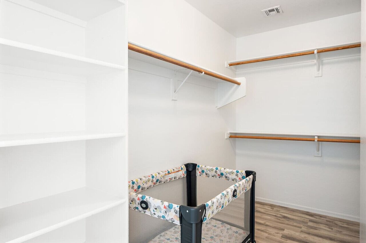 A room with white walls, wooden flooring, and a black and white patterned baby gate.