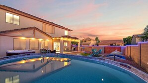 Un patio trasero con piscina, jacuzzi y mobiliario exterior.