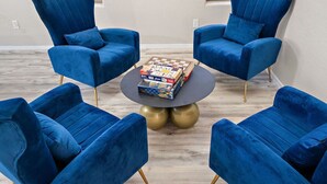 Una habitación con cuatro sillones azules dispuestos alrededor de una mesa redonda con un tablero de ajedrez.