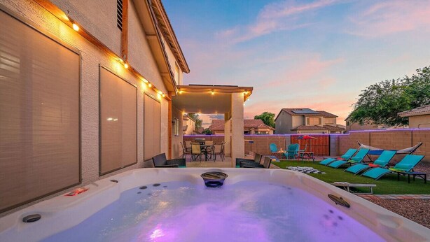 Un jacuzzi con zona de patio, mobiliario exterior y vistas a casas vecinas.
