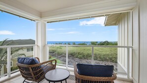 Ein überdachter Balkon mit Korbmöbeln und Blick auf den Ozean.
