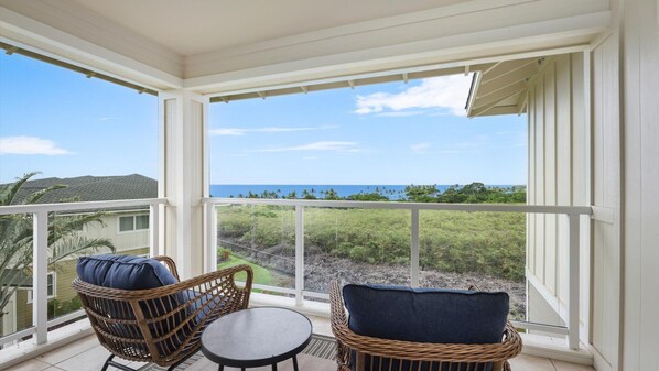 A covered balcony with wicker furniture and a view of the ocean.